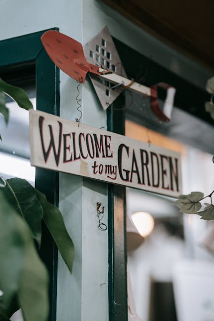 A well-maintained garden pathway leading through a landscaped outdoor space, with a gravel walkway bordered by neatly trimmed green lawns and a series of tall, slender cypress trees on either side. Th